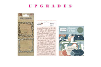 Colorful scrapbook papers and stickers in a monthly scrapbook kit featuring floral designs and cameras, ideal gifts for women