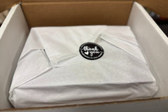We carefully package each month's box. Image shows a set of books wrapped in white tissue paper with a thank-you sticker.
