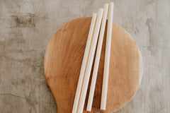 bamboo straws set of 4 on a wooden background laying on a table. They are light in color and reusable