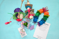 A variety of bird toys spilling out of a cardboard box and onto a blue cloth. Next to it is an itemized receipt and a business card. 