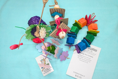 A variety of bird toys spilling out of a cardboard box and onto a blue cloth. Next to it is an itemized receipt and a business card. 