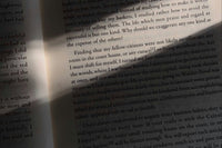 High quality closeup photo of a white book with black text. The photo is very dark but there is a beam of light in the canter.