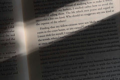 High quality closeup photo of a white book with black text. The photo is very dark but there is a beam of light in the canter.