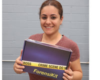 A blue box containing a forensikit is displayed in the the hands of a woman with dark hair.  she is smiling