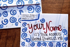 Hand-decorated patriotic envelope with red and blue swirl designs, handwritten sample name and U.S. mailing address.