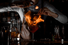 Elegant cocktail being crafted with premium ingredients, garnished with an orange peel and luxury cherries
