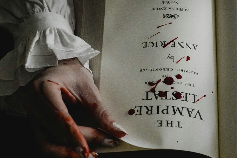 horror vampire book that has drops of dark red blood on it and a vampire looking hand holding the book.
