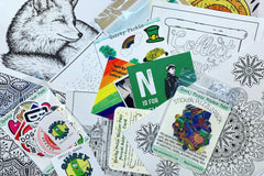Contents of a past Quirky Pickle subscriber pack, such as coloring sheets, postcards, a sticker puzzle, stickers, and stationery.