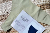 Customer photo of a green thong they received  with the subscription notecard laying on top of the thong