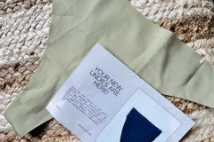 Customer photo of a green thong they received  with the subscription notecard laying on top of the thong