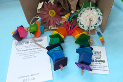 A variety of bird toys spilling out of a cardboard box and onto a blue cloth. Next to it is an itemized receipt and a business card. 