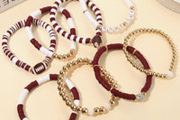 Loose Game Day stackable friendship bracelets in maroon, white, and gold beads overlapping on a light surface, showing the football charm an