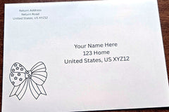 White envelope with printed sample U.S. mailing address and a black outline patriotic bow with stars in the lower-left corner.