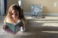 Preteen reading beside an Owl Post Books kids subscription box filled with Baby Animals and crafts, a perfect holiday gift for tweens.