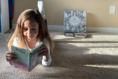 Preteen reading beside an Owl Post Books kids subscription box filled with Baby Animals and crafts, a perfect holiday gift for tweens.