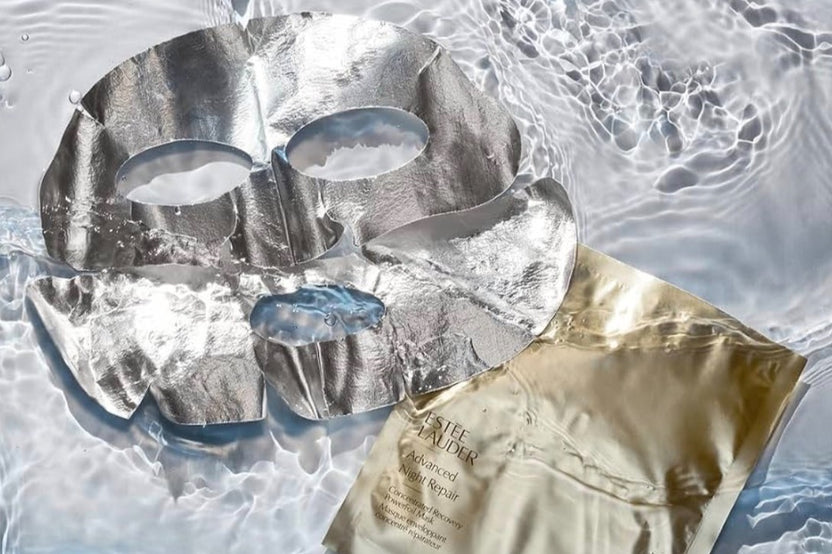 Estee lauder premium sheet mask shown with wrapper on display in  floating in water giving a luxury flay lay photo 