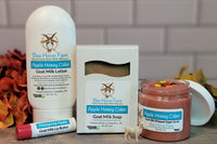 Goat milk lotion, soap, sugar scrub, and lip butter in Honey Apple Cider scent surrounded by fall foliage.