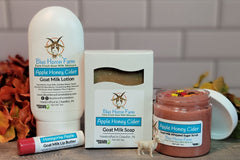 Goat milk lotion, soap, sugar scrub, and lip butter in Honey Apple Cider scent surrounded by fall foliage.