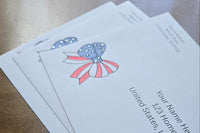 Three white envelopes with printed sample U.S. addresses and a red, white and blue patriotic bow design featuring stars and stripes.