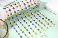 Evil eye bracelets with blue glass charms draped in rows on a mint green background, showing 14K gold plated gold-tone chains in detail.