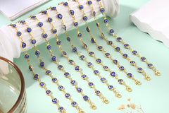 Evil eye bracelets with blue glass charms draped in rows on a mint green background, showing 14K gold plated gold-tone chains in detail.