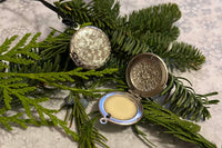 A beautiful locket with a solid anointing ritual oil, set on a bed of cedar and pine. This oil was hand crafted and poured. Created for Yule