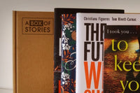 Brown box filled with a diverse collection of books in multiple genres, including crime thrillers, romance, and fantasy
