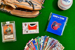 Baltimore Orioles baseball cards arranged in flat lay format on a green carpet and with a baseball glove and ball