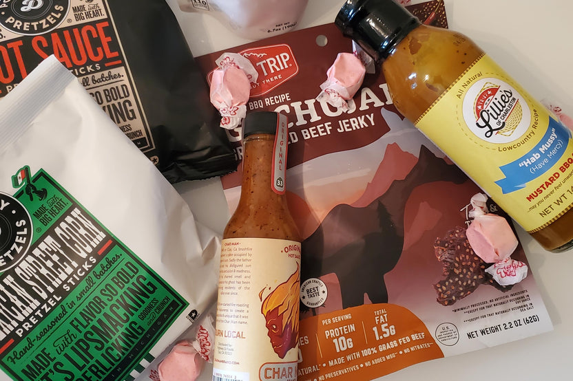 Hot Stuff spicy food snacks flat lay includes hot sauce, jerky, candy, pretzels and other items. Example of the products included in our box