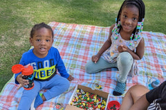 customer provided photo of her 2 children playing with the very hungry caterpillar inspired sensory bin while on a picnic.