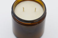 Top view of an unlit 16oz Burlap Bag soy candle showing two cotton wicks set in smooth cream soy wax inside the amber jar