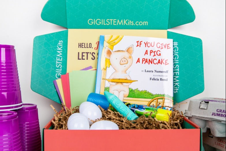 A GIGIL STEM Kit showing cups stacked, plastic eggs, construction paper, "If You Give a Pig a Pancake" book, sidewalk chalk, egg carton