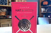 Learn to Knit Hat & Mitts knitting kit for beginners - box on tabletop with yarn shop background - brown yarn showing through the box
