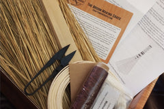 Contents of our Broom Making Crate including broomstraw, a straw nipper, waxed thread, reed, dye, instructions, a dowel, more.