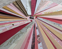 Deep red, pink, gold and pattered paper strips fanned out in a circle to show all the detail on each.