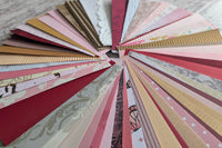 Deep red, pink, gold and pattered paper strips fanned out in a circle to show all the detail on each.