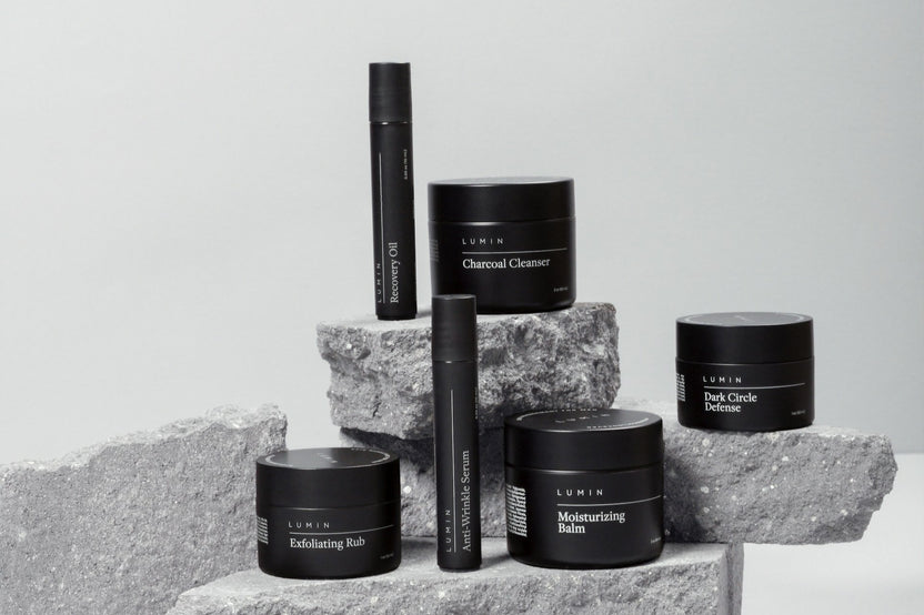 High quality photo of 6 mens self care and skin care products in black color. With the products standing on rocks
