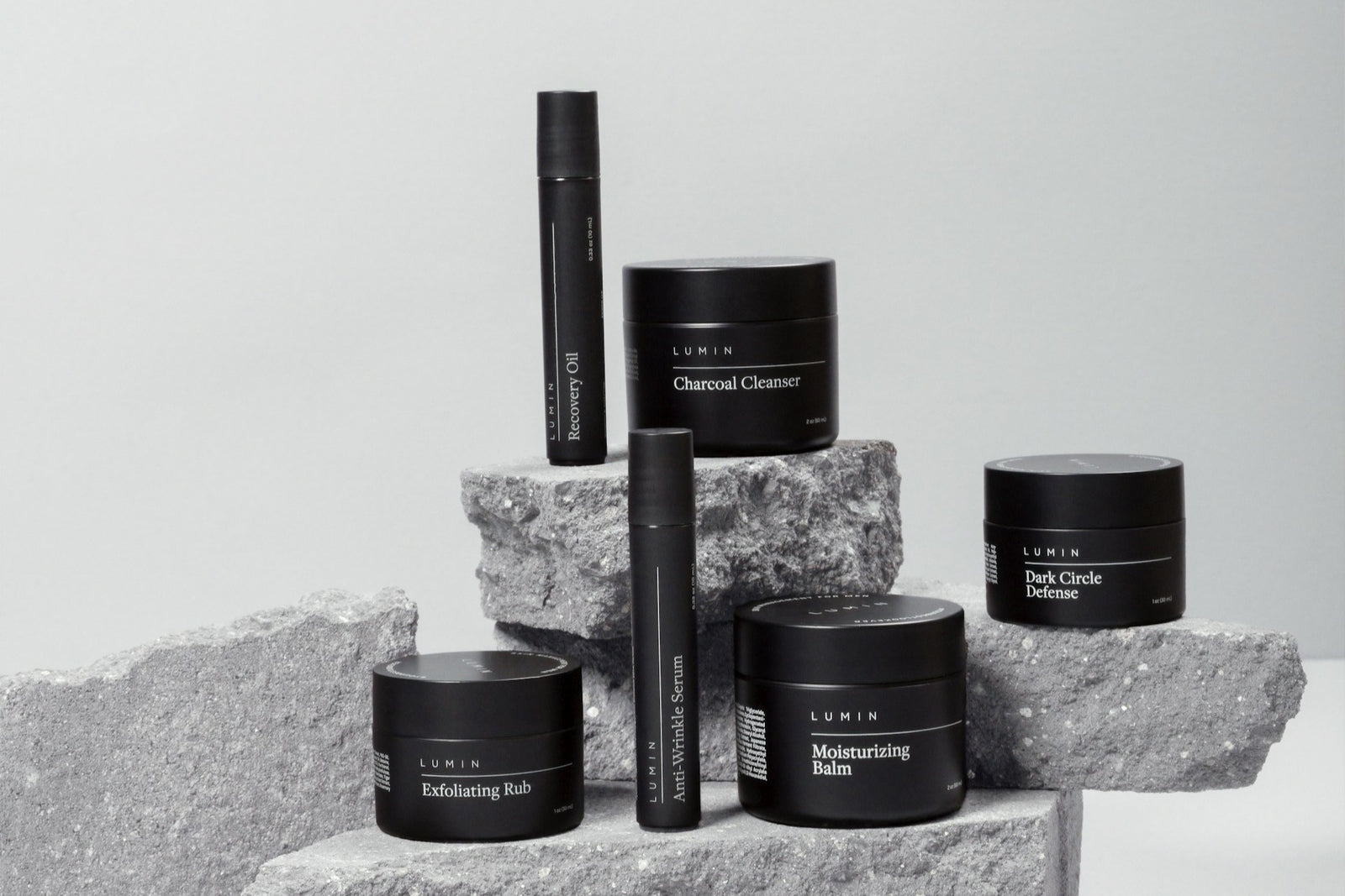 High quality photo of 6 mens self care and skin care products in black color. With the products standing on rocks