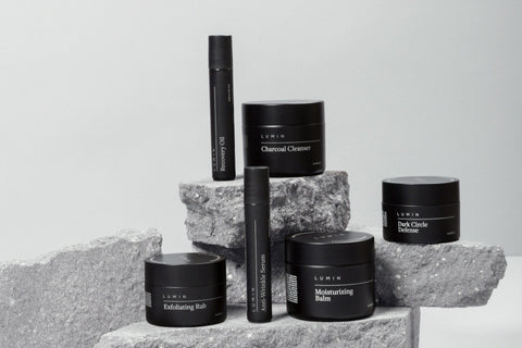 High quality photo of 6 mens self care and skin care products in black color. With the products standing on rocks