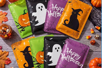 8 Halloween sheet mask shown on a wooden floor in a flay lay position with  candy and pumpkins giving the photos spooky Halloween vibes