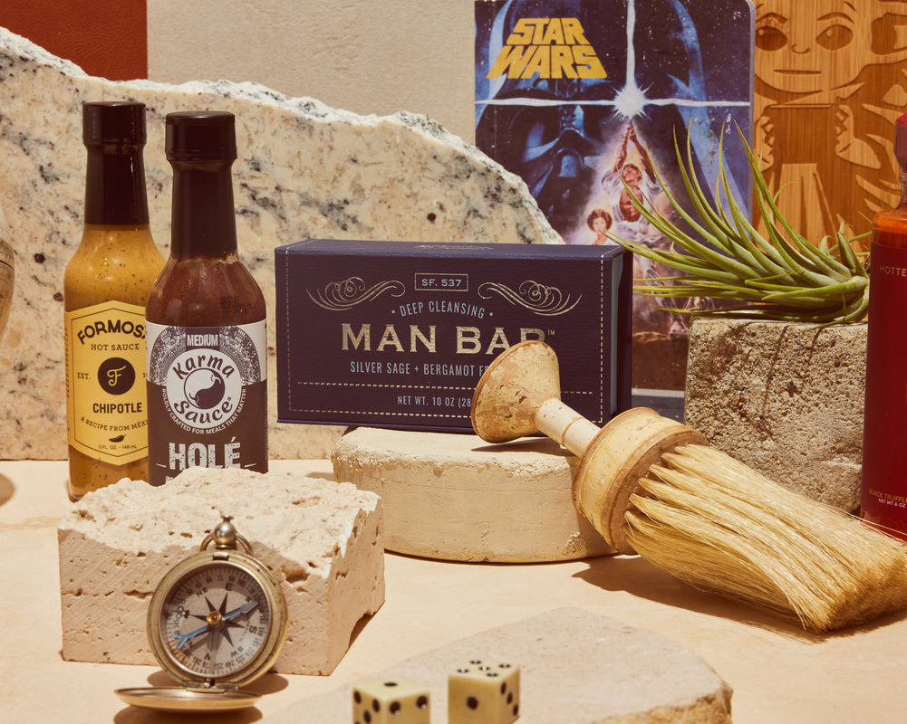 Professional product shot of hot sauce, soap, a brush, Star Wars comic, games, watch