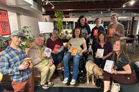 Diverse group of You Should Read book club members smiling and holding books during a cozy in-person meetup