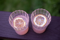 Cute swirly glassware with pink lemonade and freeze dried lemon slices sitting on the balcony of a deck