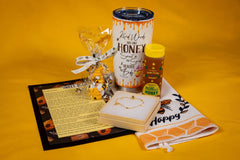 Bee Kind Appreciation Box gift set with bee mug, honey, bracelet, gnome, towel, and inspirational story card on yellow background.