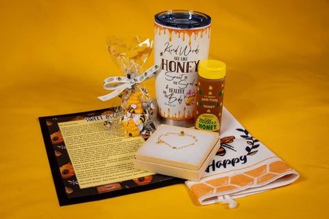 Bee Kind Appreciation Box gift set with bee mug, honey, bracelet, gnome, towel, and inspirational story card on yellow background.