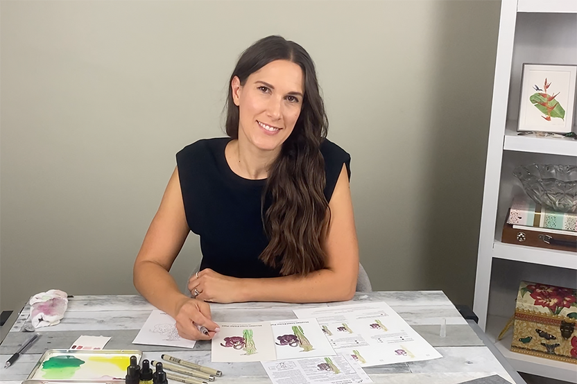 Instructor Stephanie Rozzo demonstrating how to paint a beautiful watercolor and ink pitcher plant at a desk.