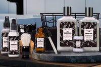 Close up photo of many skin care products for men lined up next to each other with a bathroom in the background.