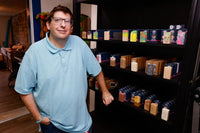 Robby Sihto, who makes SoapyFluffs soap, in his shop in Hamilton, Ohio, beside black shelves stocked with his soap bars