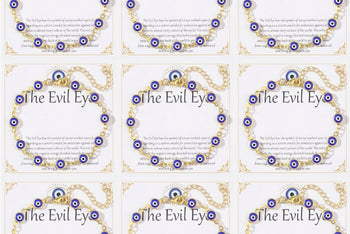 Nine 14K gold plated evil eye bracelets displayed on white 'The Evil Eye' gift cards, each with blue evil eye charms on a gold-tone chain.