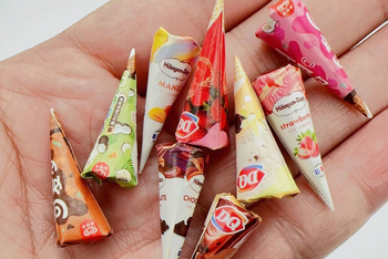 This is a photograph of  tiny miniature ice cream cones.  There are many flavors of ice cream to choose from .